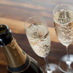 High Angle Close Up View of Open Champagne Bottle with Two Flutes Filled with Carbonated White Wine on Wooden Table with Copy Space - Celebration Concept Image